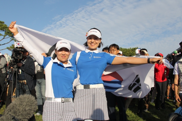 먼저 경기를 끝낸 김인경과 전인지(좌로부터)가 18번 홀에서 경기를 하고 있는 유소연 선수를 응원하며 태극기를 등 뒤로 펼쳐 보이고 있다(사진 제공: UL 인터내셔널 크라운 조직위원회)